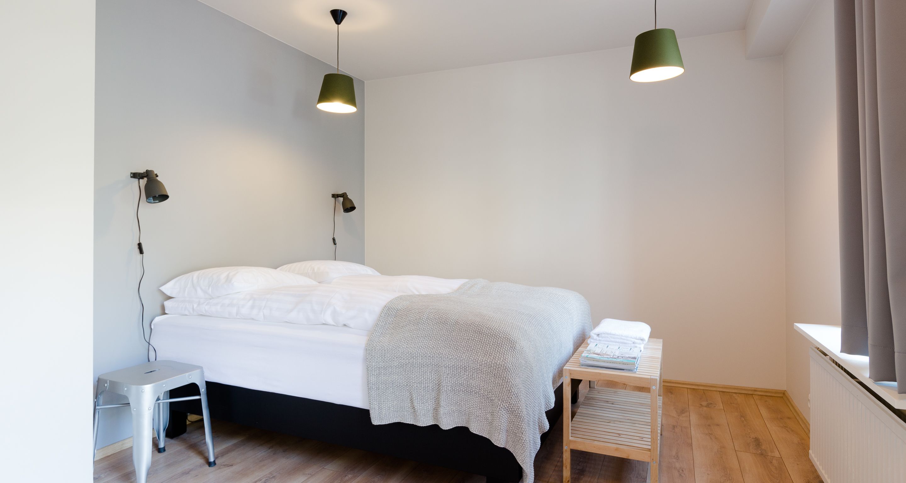 A bedroom with a bed, bedside tables, and two pendant lights.