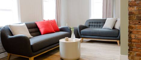 A modern living room with two sofas, a round side table, and a brick accent wall.