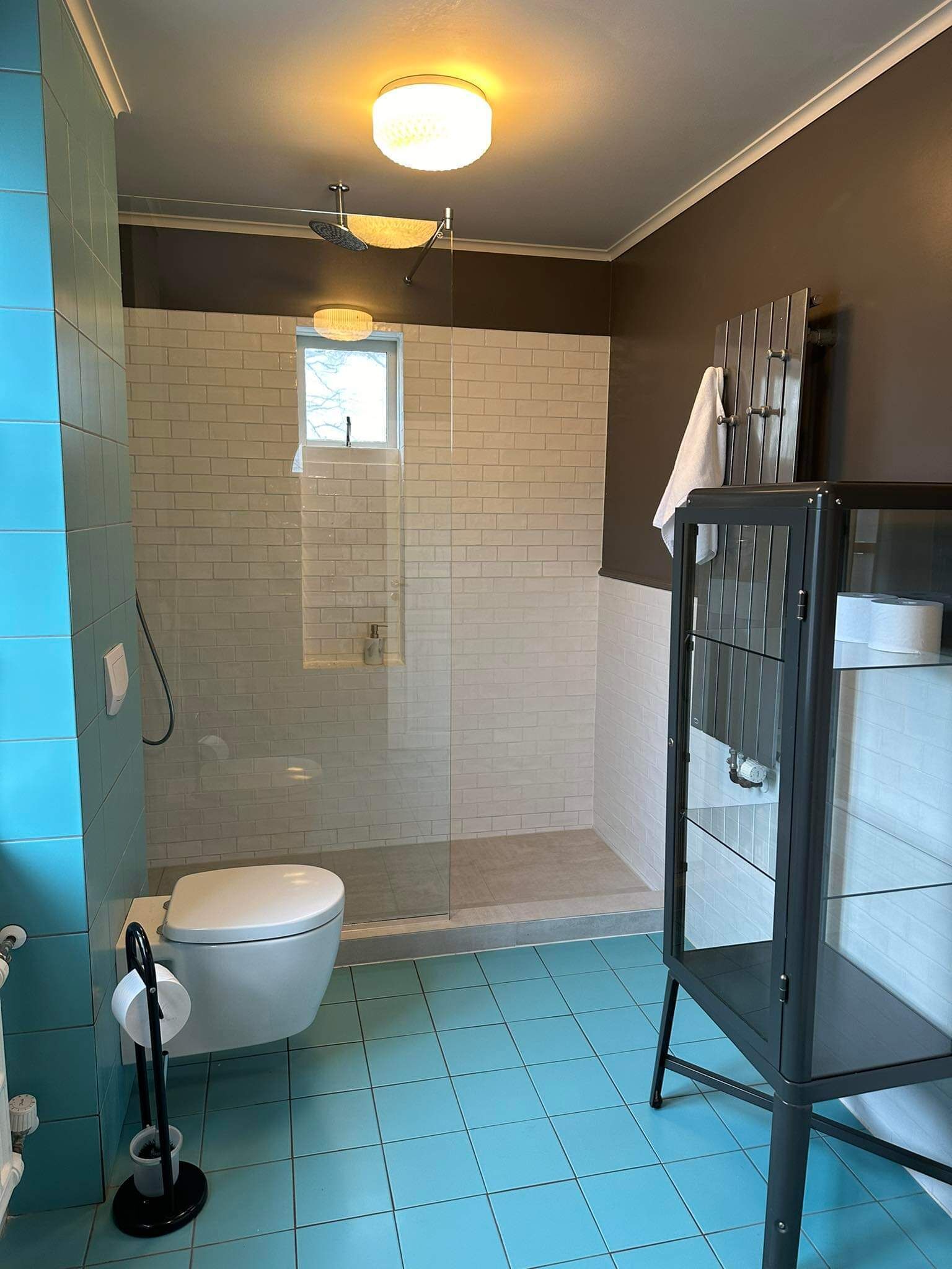 Une salle de bain comprenant des toilettes, une douche avec une porte en verre et un porte-serviettes.