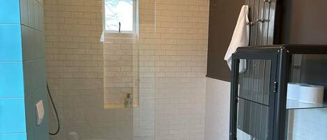 Une salle de bain comprenant des toilettes, une douche avec une porte en verre et un porte-serviettes.