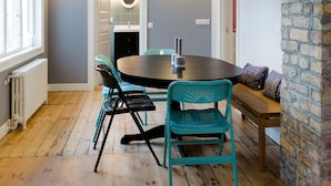 Un comedor con una mesa redonda, sillas color turquesa y una lámpara colgante.