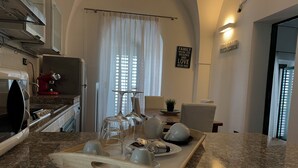 Una cocina con encimeras de granito, una cafetera y un comedor con una mesa dispuesta para dos.