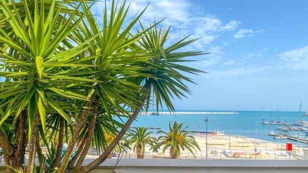 Un balcón con vistas a un puerto deportivo y una playa.