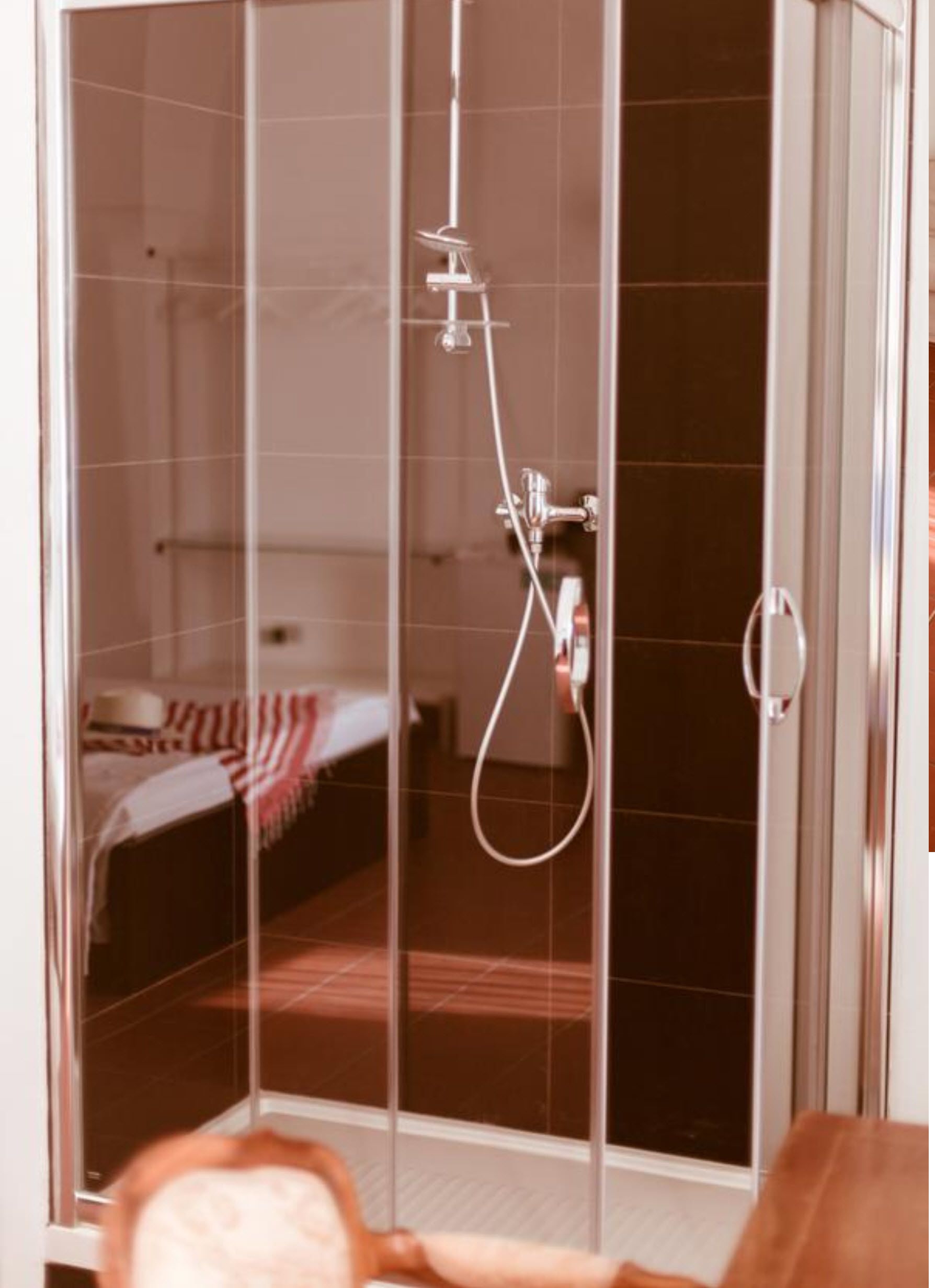 Une salle de douche entièrement vitrée, avec un lit visible à travers la vitre.