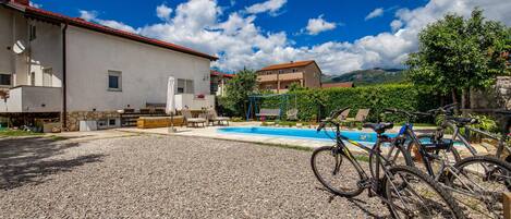 A pool area with a gravel surface, a swing set, and bicycles parked near the pool.