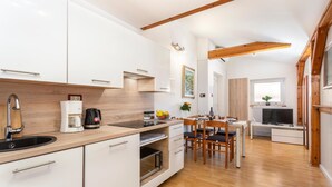 Een moderne keuken met witte kastjes, een houten aanrechtblad en een eethoek met een tafel en stoelen.