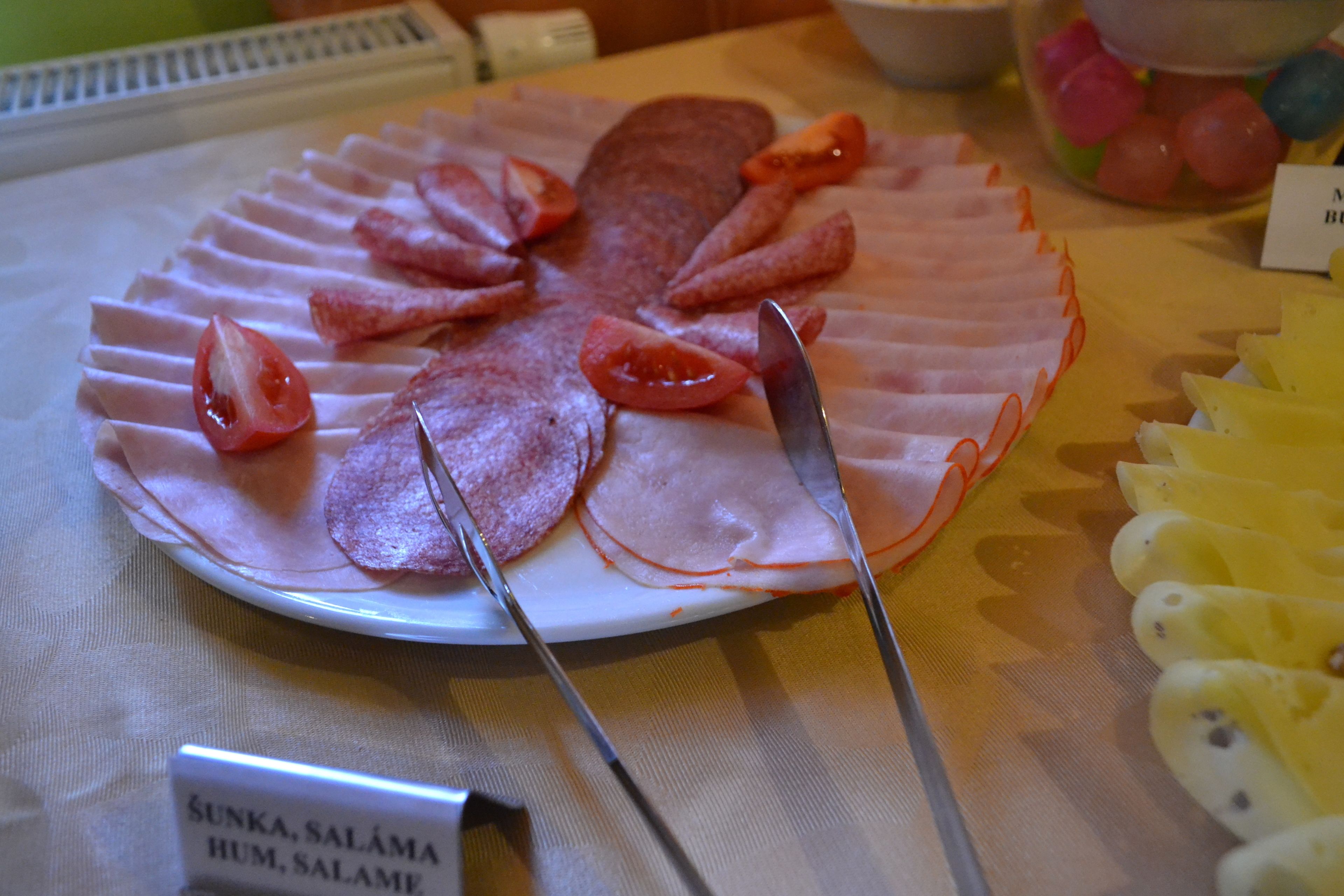 A platter of sliced meats and tomatoes on a table.