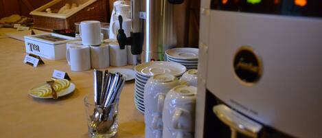 Una mesa de buffet con estaciones de té y café, incluyendo una cafetera y un termo.