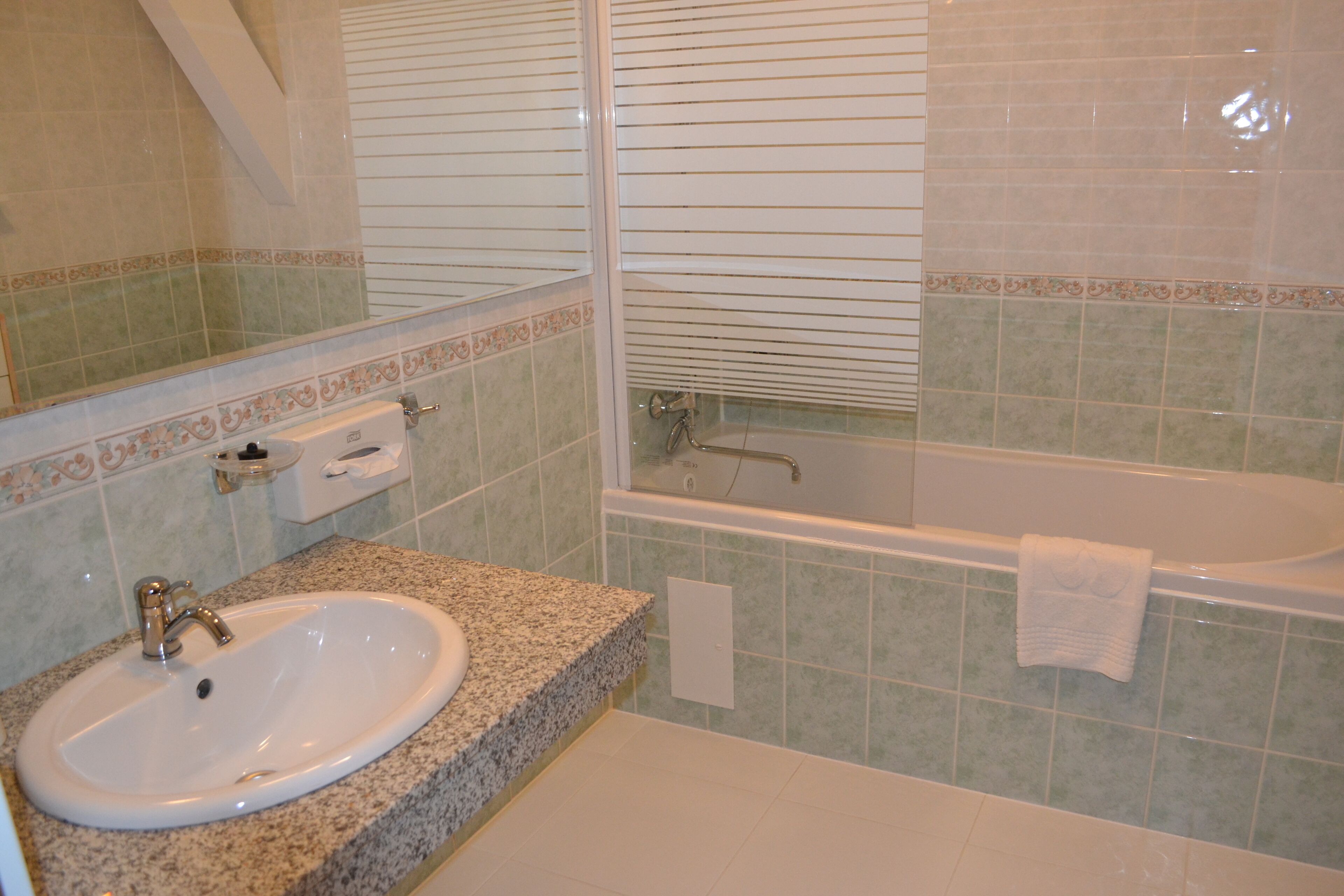 A bathroom with a sink, mirror, and bathtub.