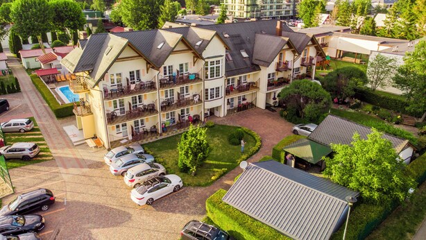 A multi-story hotel with a central courtyard, outdoor seating, and a swimming pool.