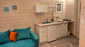 A compact kitchen with wooden walls, a sink, a stove, and a small countertop.