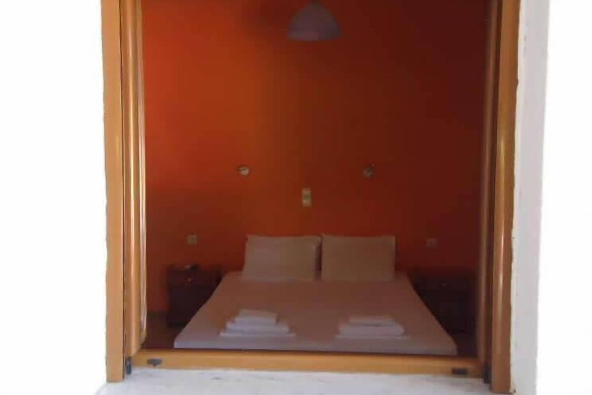 A room with a bed, two pillows, a nightstand, and a hanging light fixture.