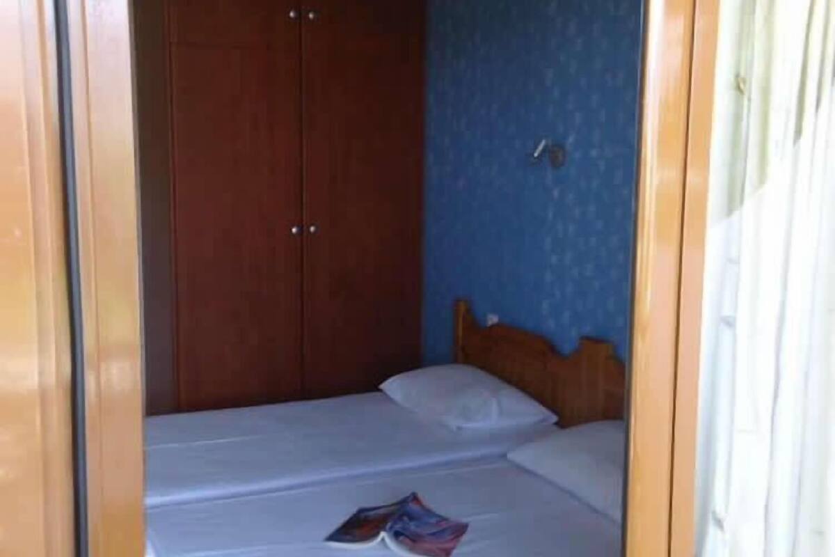 A small, single-bed room with a wooden wardrobe and a blue wall.