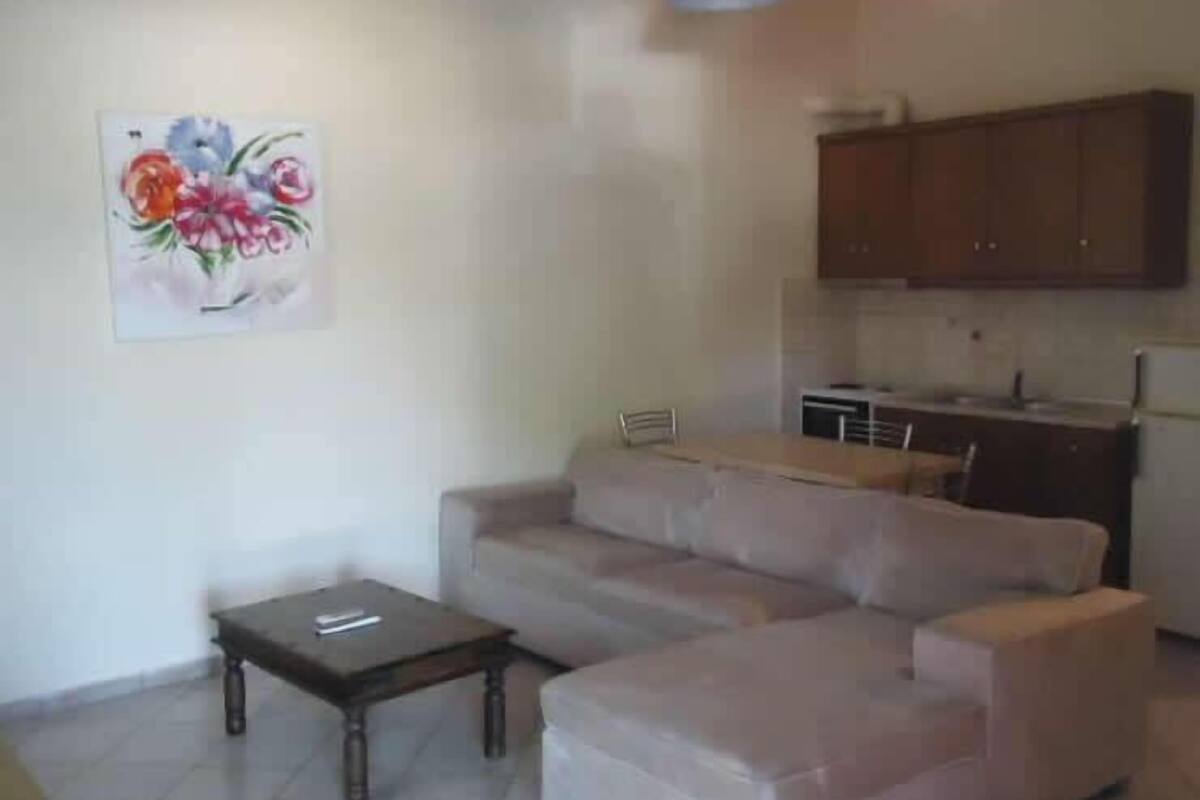 A living room with a sofa, a small table, and a kitchen area in the background.