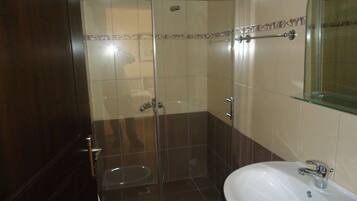 Un baño con cabina de ducha de vidrio, un lavamanos blanco y un inodoro.