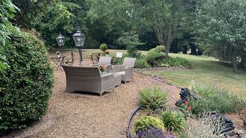 Een tuinpatio met wicker meubilair, een tafel en twee lantaarns.