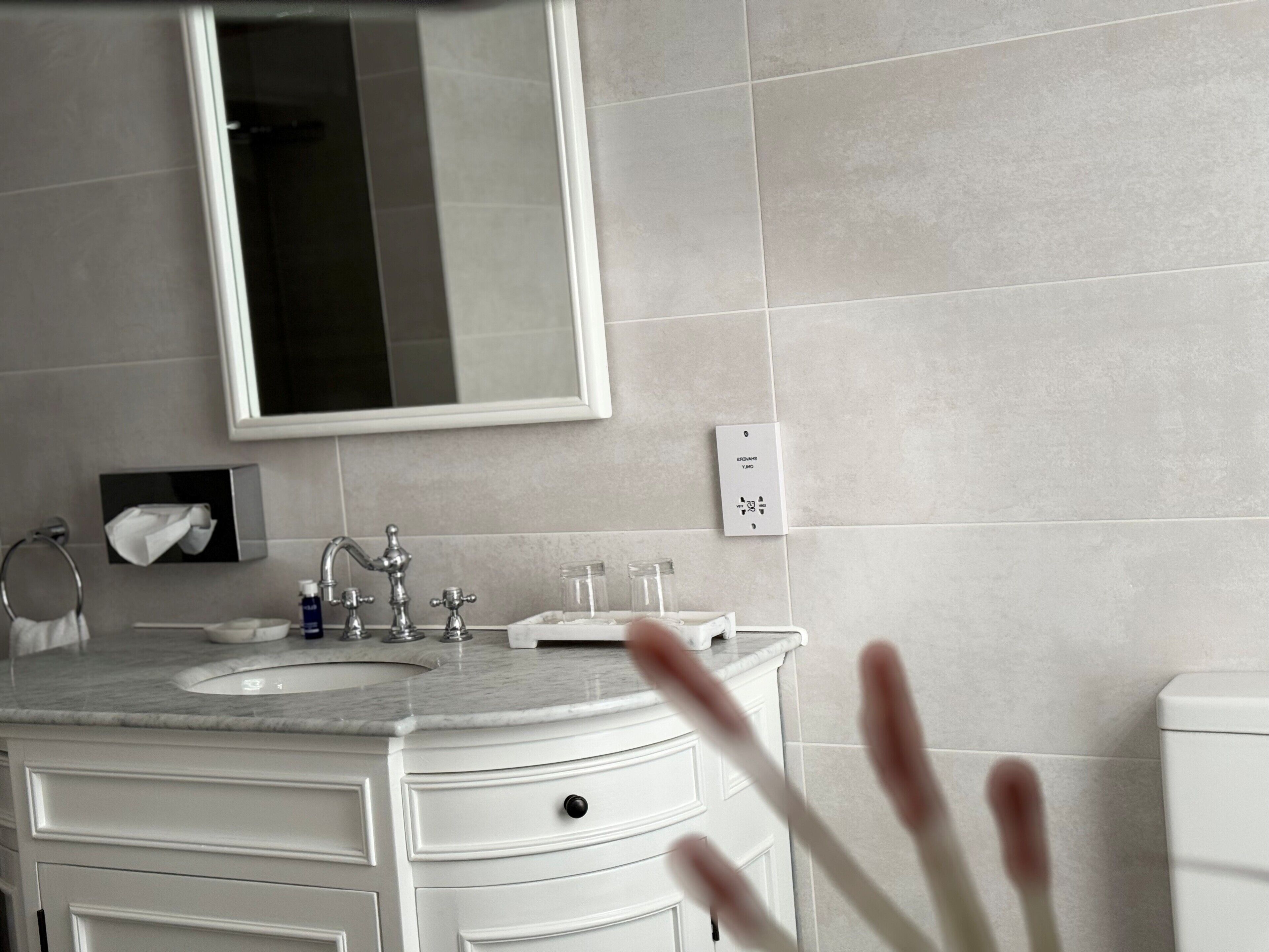 A bathroom with a sink, mirror, towel rack, and a toilet.