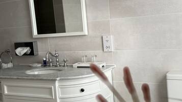 A bathroom with a sink, mirror, towel rack, and a toilet.