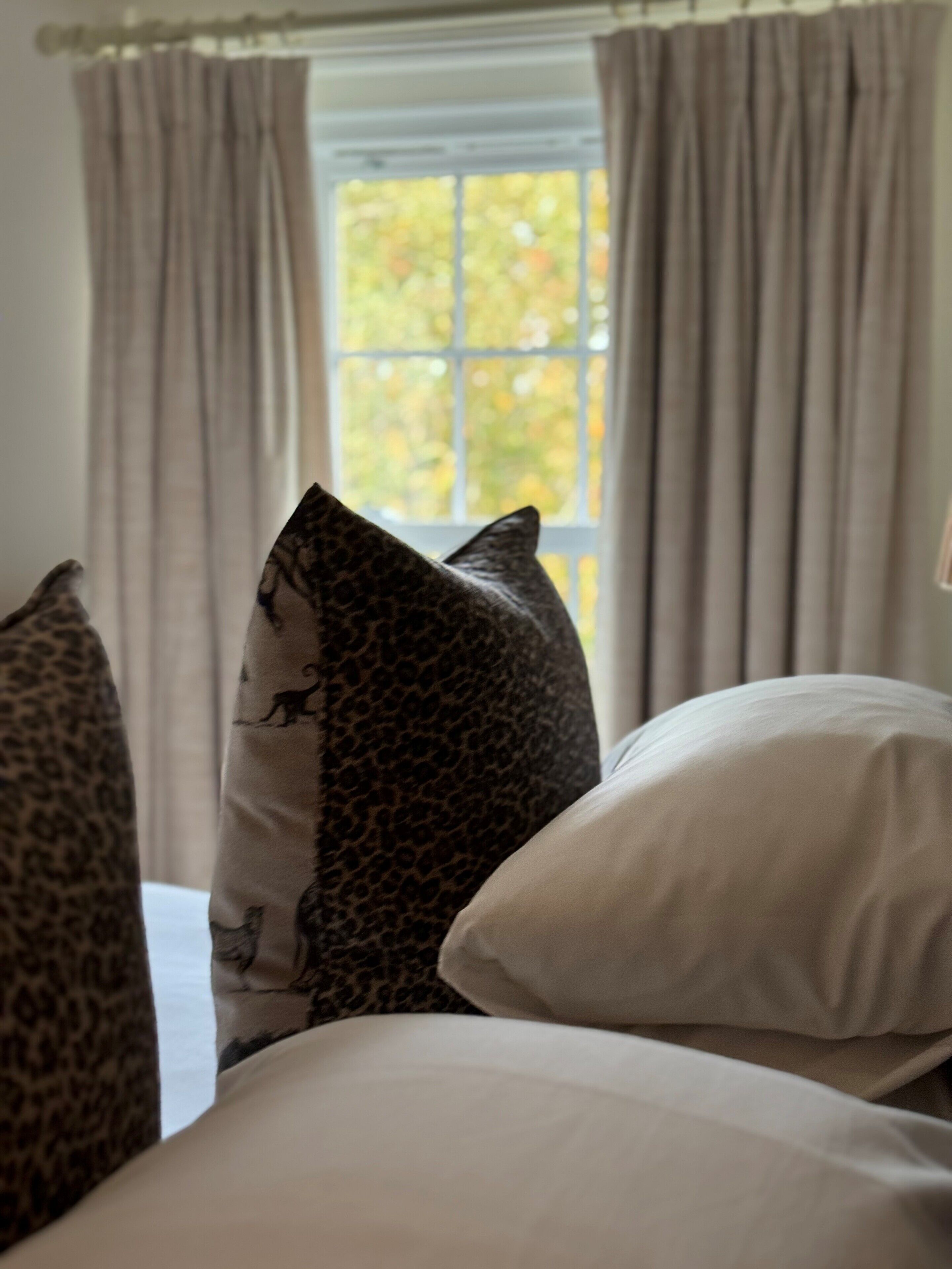Una cama con dos almohadas, una con estampado de leopardo y otra lisa.