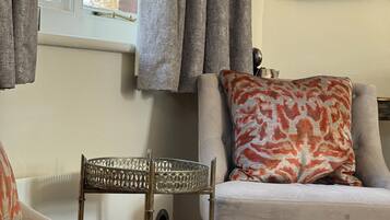 A room with a bed, a chair, a window with curtains, a radiator, and a framed picture on the wall.