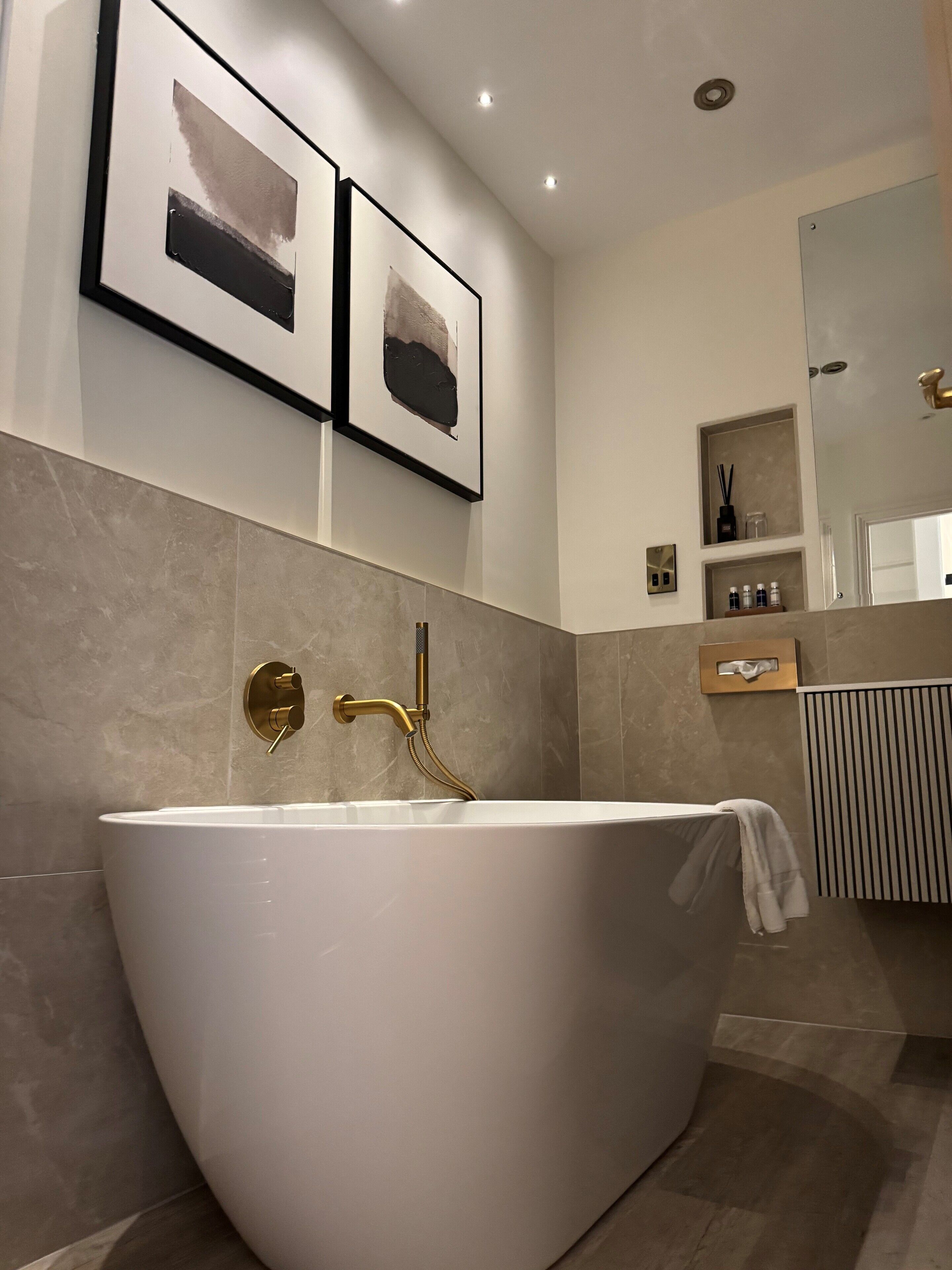 A modern bathroom with a freestanding bathtub, a wall-mounted sink, and a large mirror.