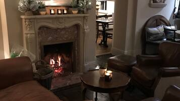 A cozy living room with a fireplace, comfortable seating, and a dining area in the background.