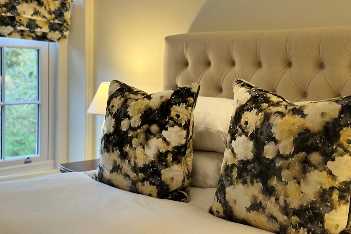 A bed with two patterned pillows and a tufted headboard.