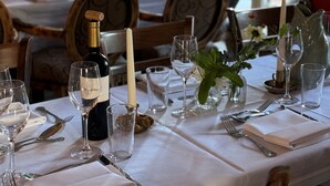 A dining table set with wine glasses, a bottle, and candles, with a view of a brick wall and a window. - Scarborough Hill Country Inn (North Walsham)