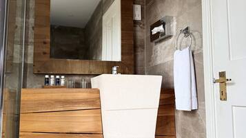 A bathroom with a wooden vanity, a white sink, a large mirror, and a towel hanging on a hook.