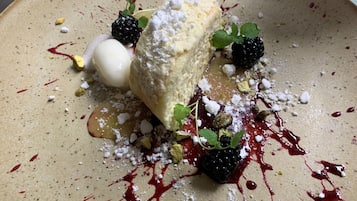 Dessert mit einer Kugel Eis, Kuchenstück und Beeren auf einem Teller.