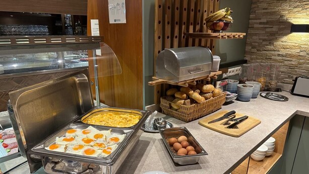 Una barra de desayuno con huevos revueltos, huevos Benedictinos y una variedad de panes y pasteles.