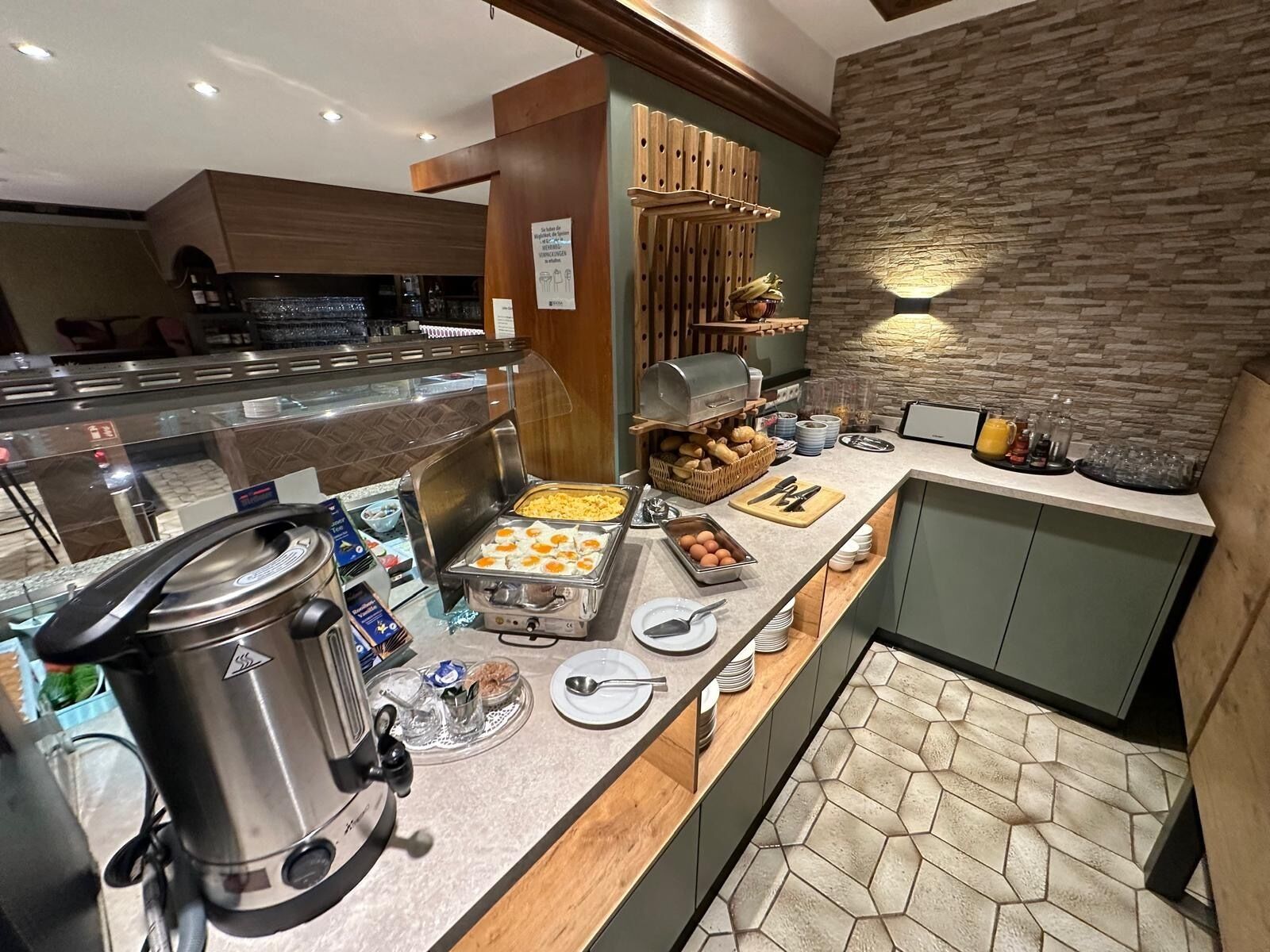 A buffet setup with a coffee maker, a grill, and various food items.