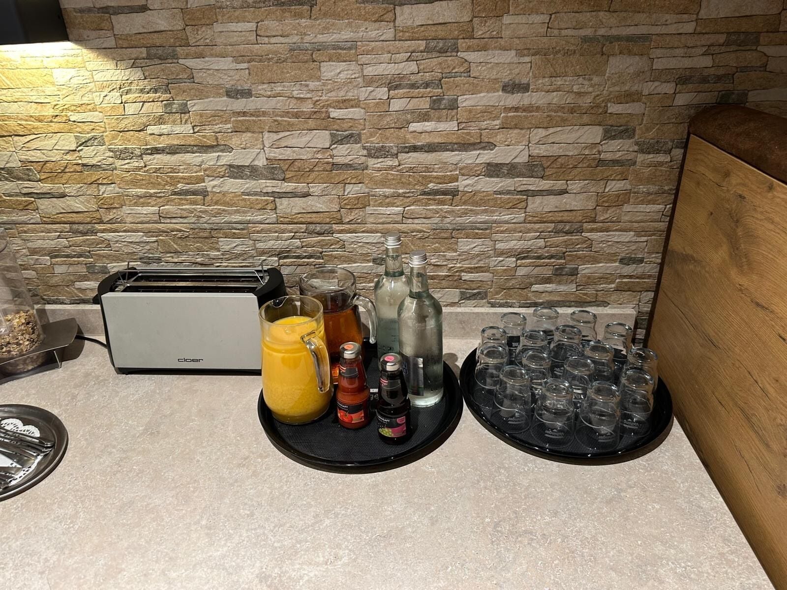 Una kitchenette con pared de piedra, un tostador, una licuadora y diversos vasos y botellas.