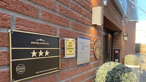 Una pared de hotel con una placa que indica un premio de 2022 de DEHOGA, un letrero de servicios de gas y un logotipo de HOTELSTARS.EU.