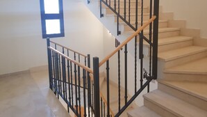 Una escalera con barandillas negras y pasamanos de madera que conduce a un piso superior.