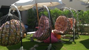 Mobiliario exterior con sombrillas y sillones colgantes en un patio.