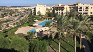 Un resort con varias piscinas, palmeras y vista al mar.