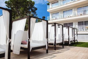 A row of four four-poster beds with white canopies, wooden frames, and a green lawn in the background. - BQ Bulevar Peguera Hotel - Adults Only (Calvia)