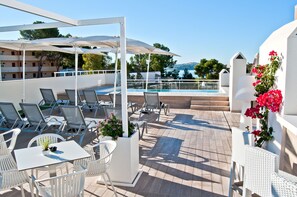 A rooftop terrace with outdoor seating, a pool, and a view of the sea. - BQ Bulevar Peguera Hotel - Adults Only (Calvia)