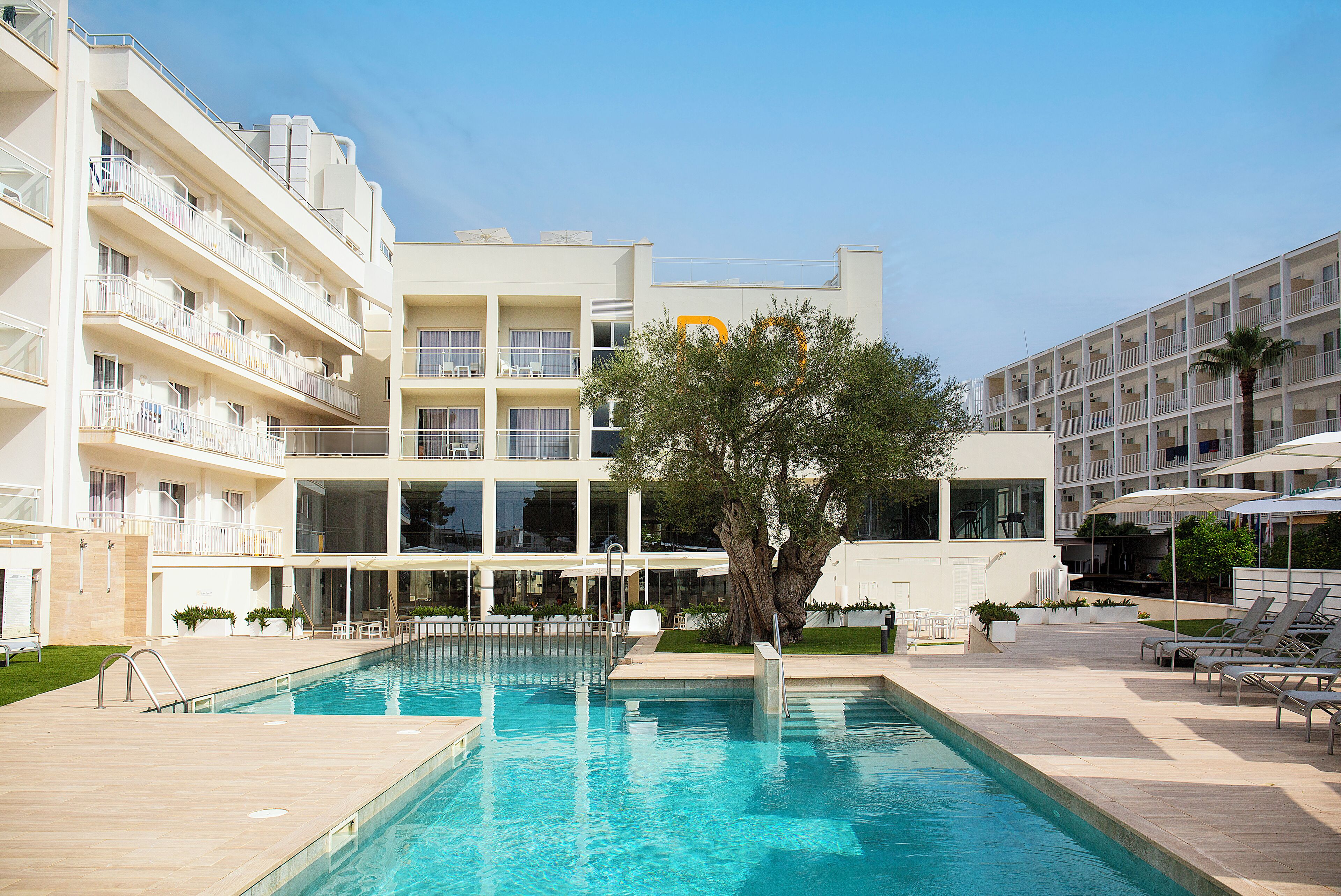 A modern hotel with a swimming pool, multiple balconies, and outdoor seating areas.
