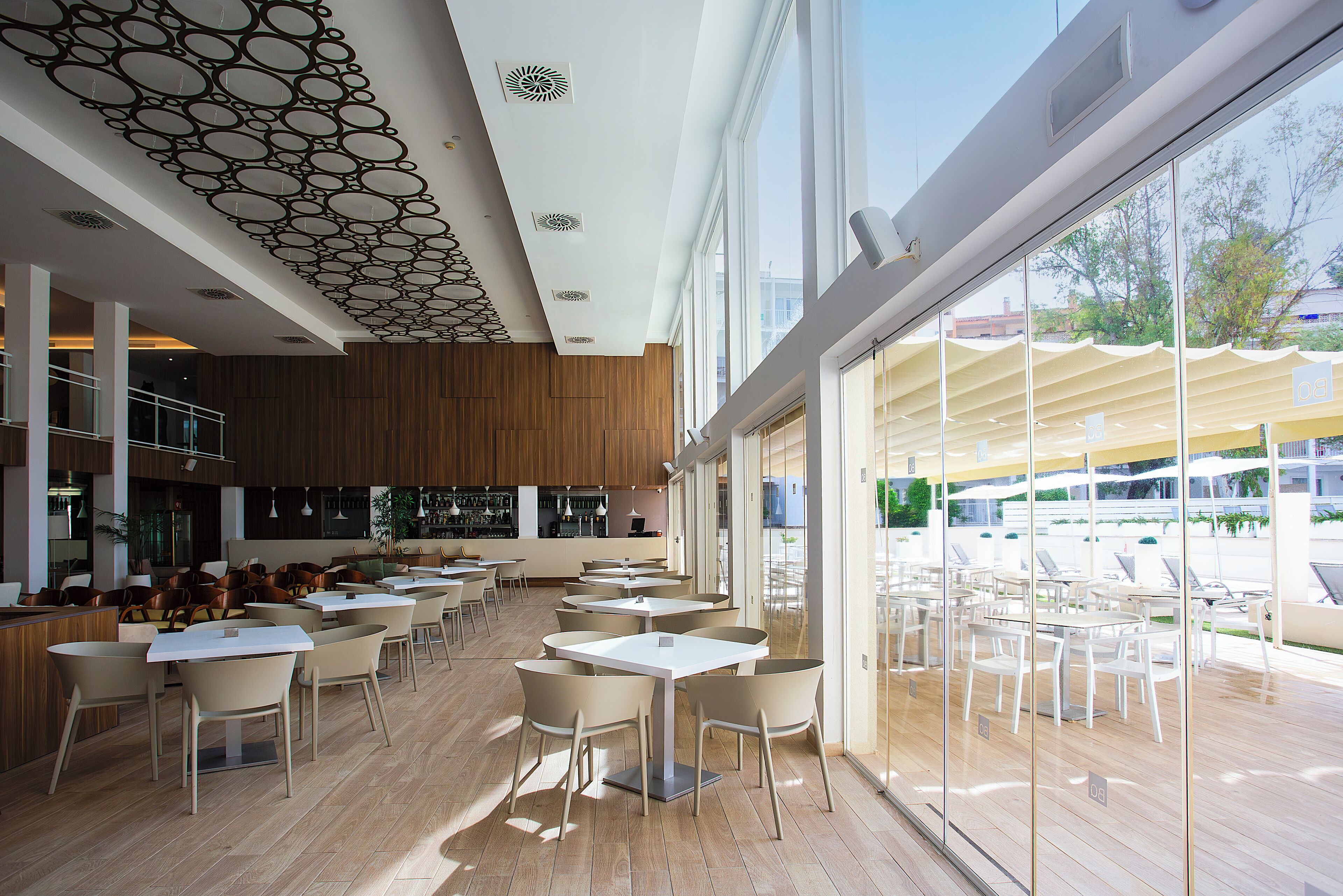 A spacious indoor dining area with high ceilings, modern lighting, and large windows offering views of the outdoors.