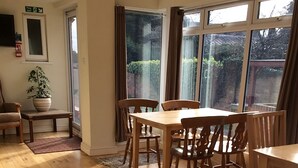 Un coin repas avec une table et des chaises en bois, un grand tapis et une vue par les fenêtres.