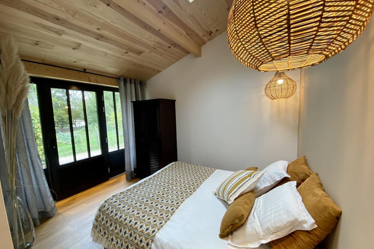 A bedroom with a bed, a wardrobe, and a large window.