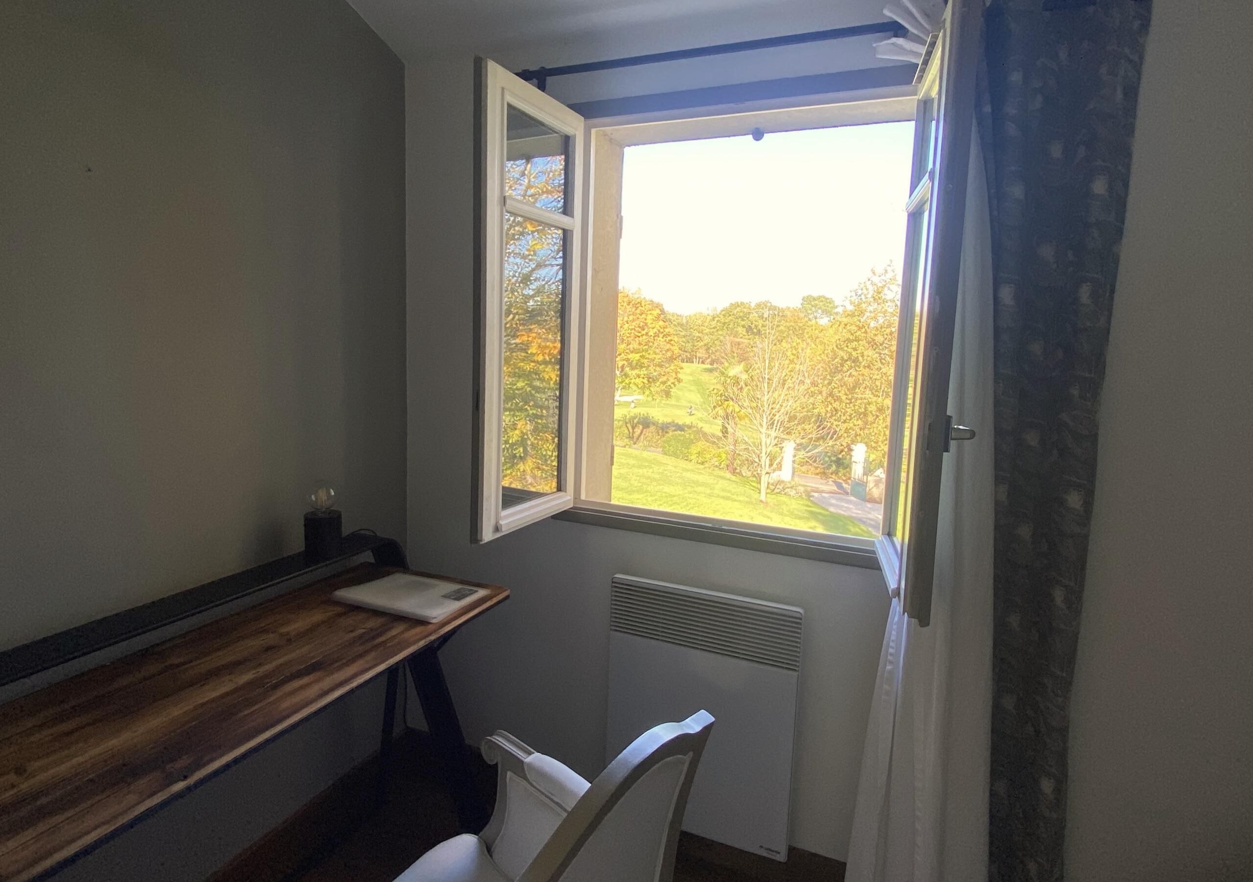Een hoekzaal met raam, een radiator, een bureau en een stoel.