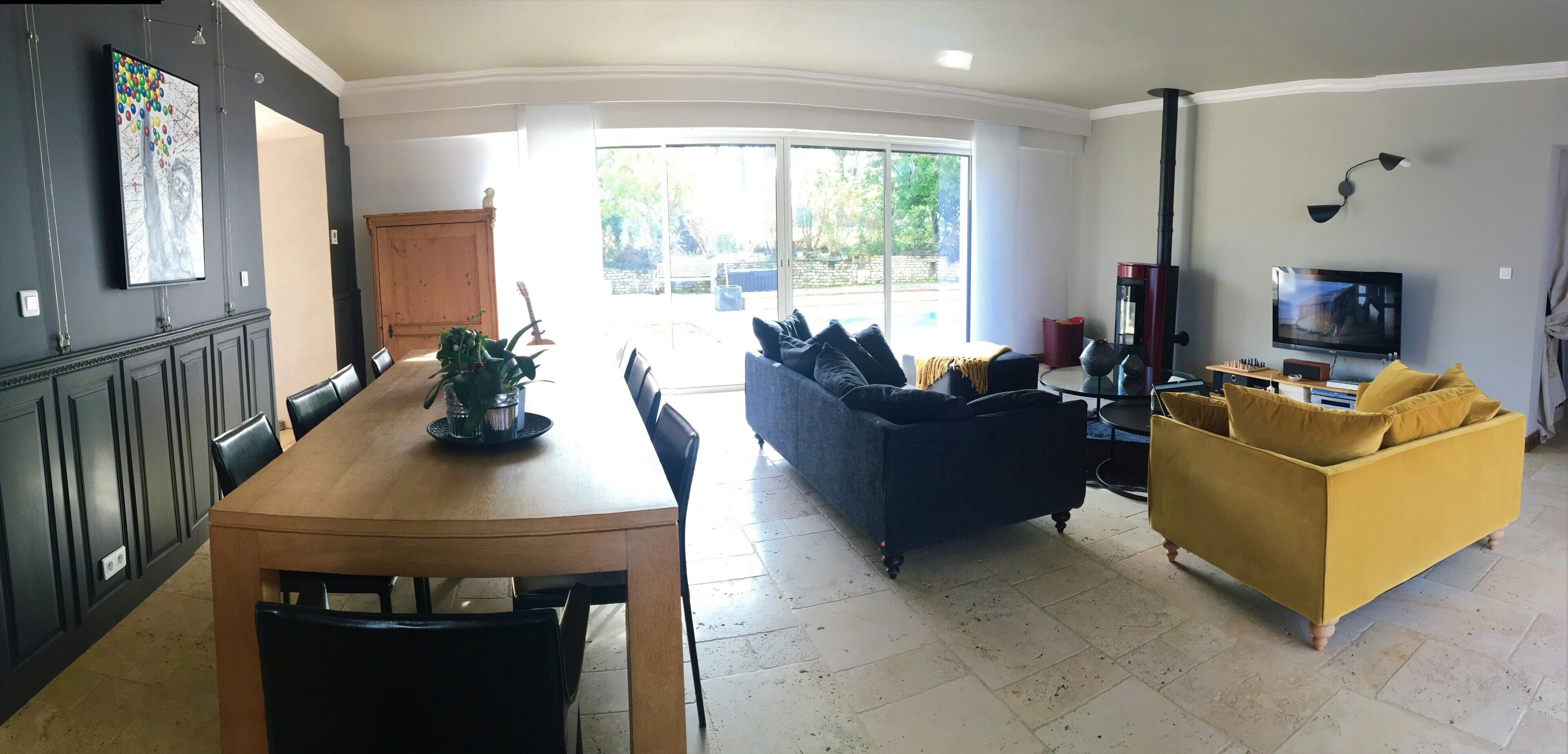Ein geräumiger Wohnbereich mit Esstisch, Sofa und Fernseher.