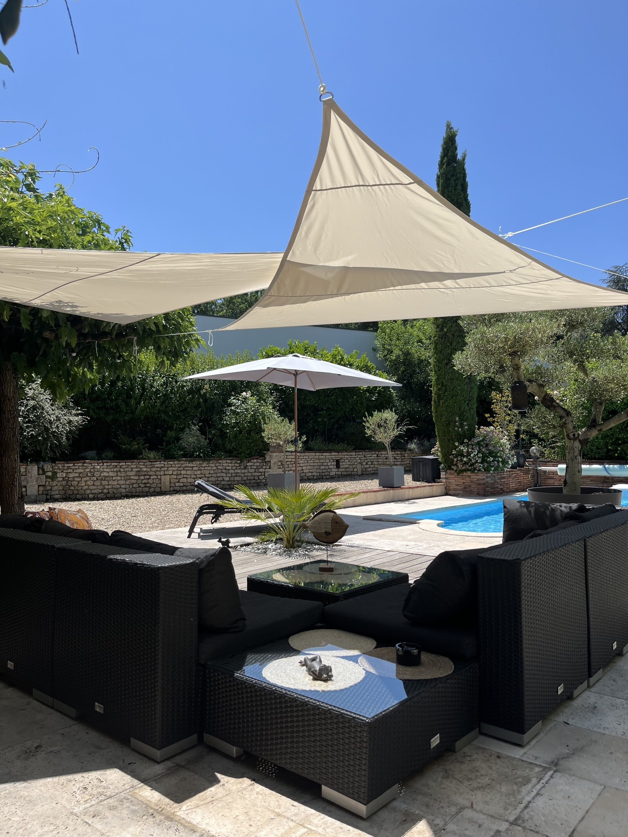 Un patio con mobiliario exterior, piscina y una gran marquesina que proporciona sombra.