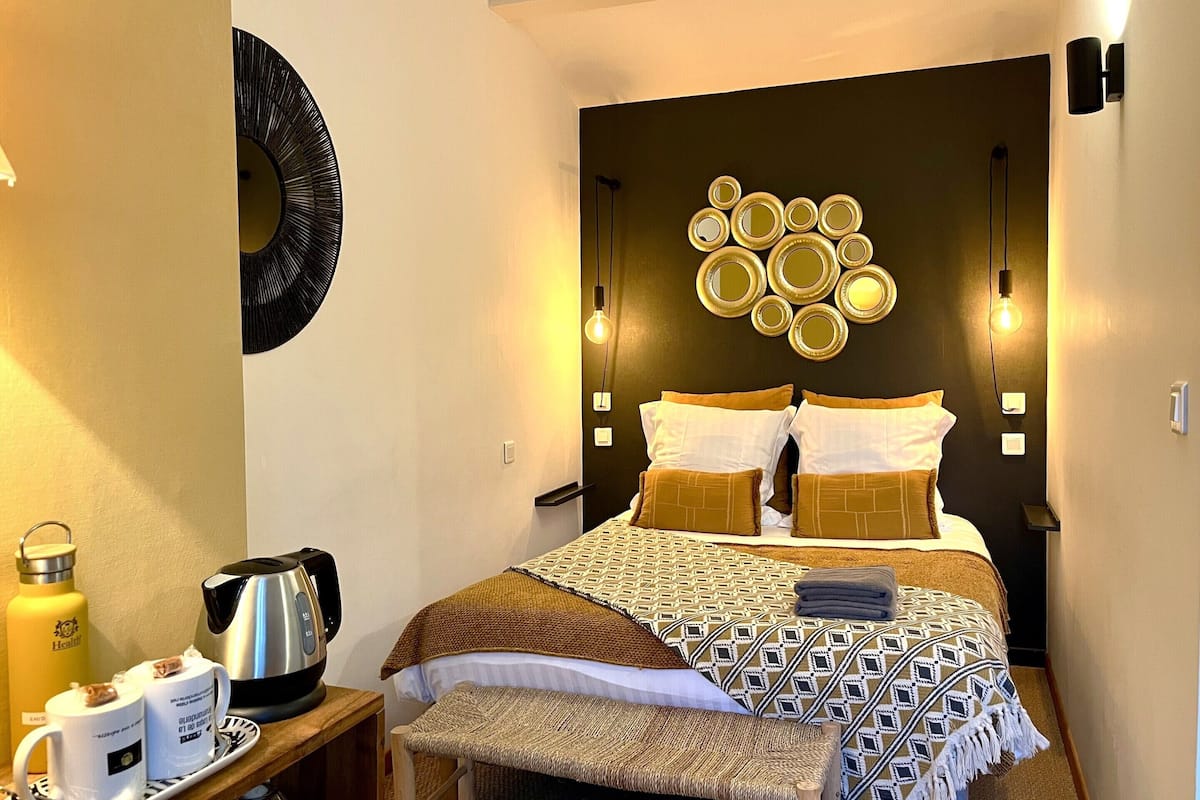 A hotel room with a bed, bedside tables, a coffee maker, and a wall-mounted light fixture.