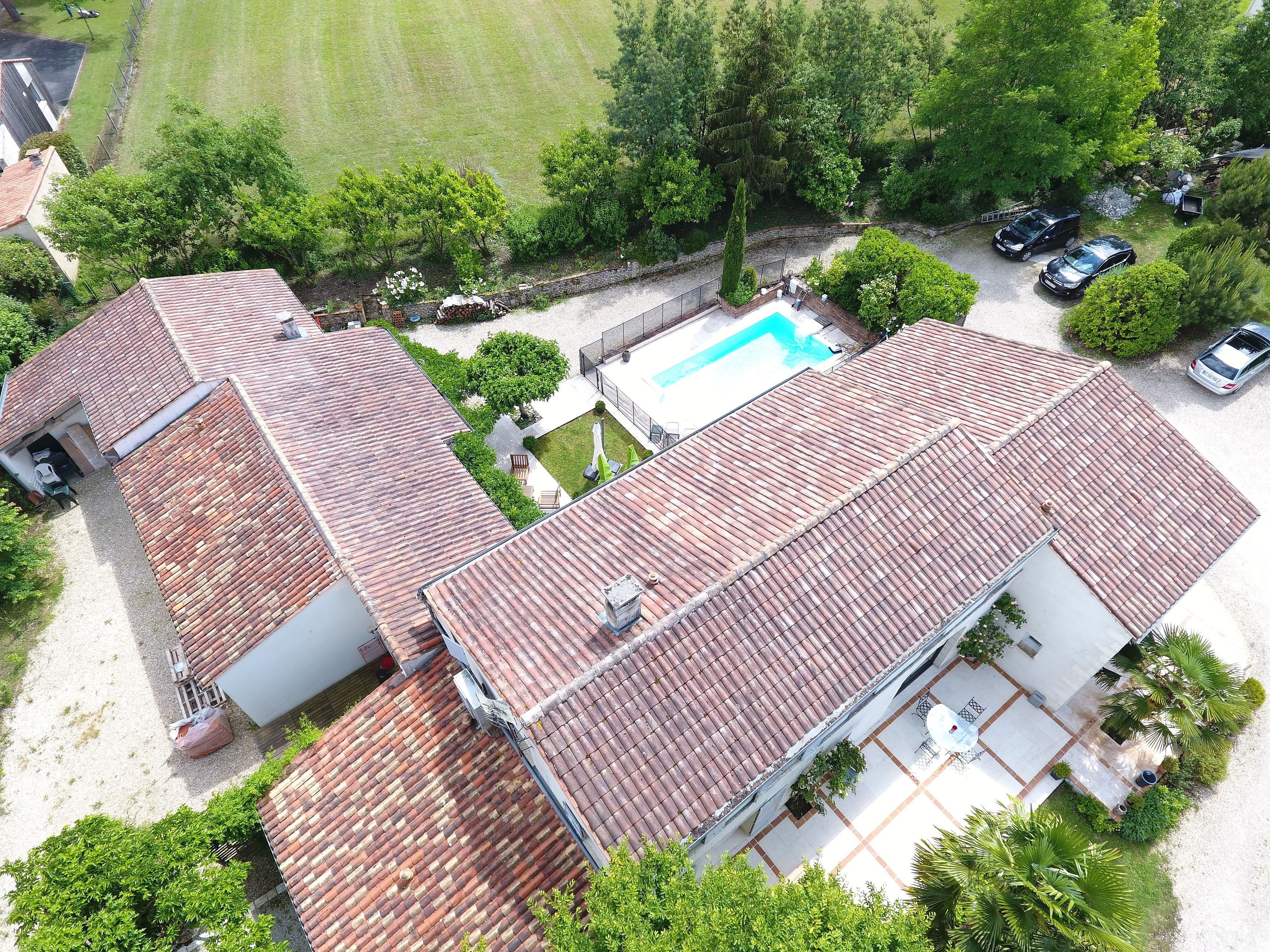 A two-story house with a tiled roof, a swimming pool, and a fenced yard.