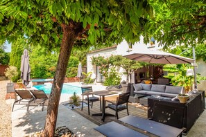 A patio area with a pool, outdoor furniture, and a covered seating area. - Logis de La Brumanderie (Fontcouverte)