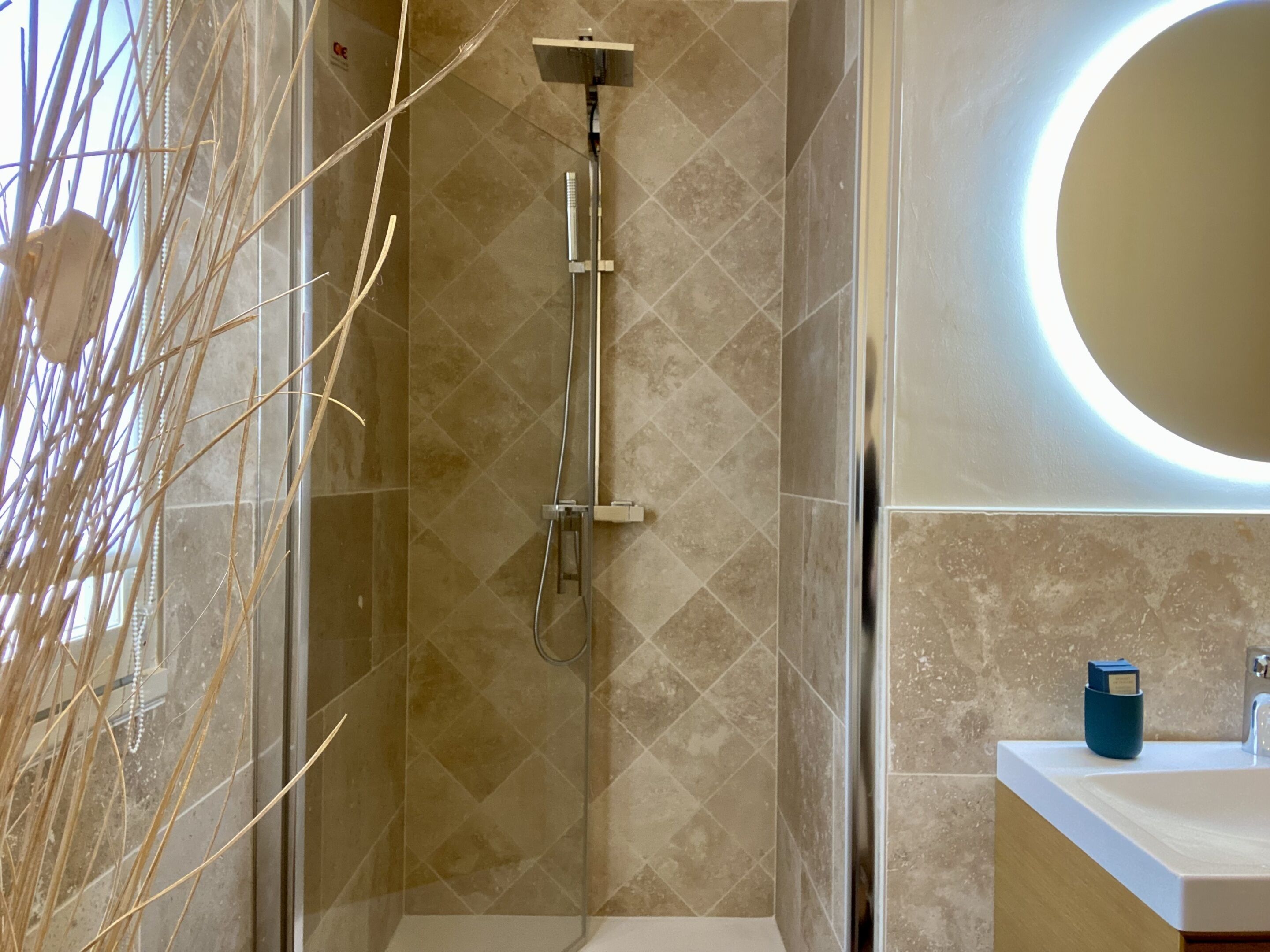 Een moderne badkamer met een douche, wastafel en spiegel.